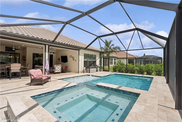 view of swimming pool with glass enclosure, ceiling fan, a patio, and an in ground hot tub