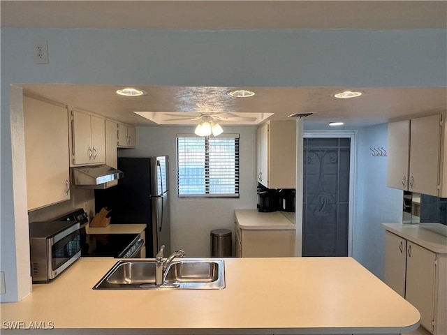 kitchen with kitchen peninsula, appliances with stainless steel finishes, ceiling fan, sink, and white cabinetry