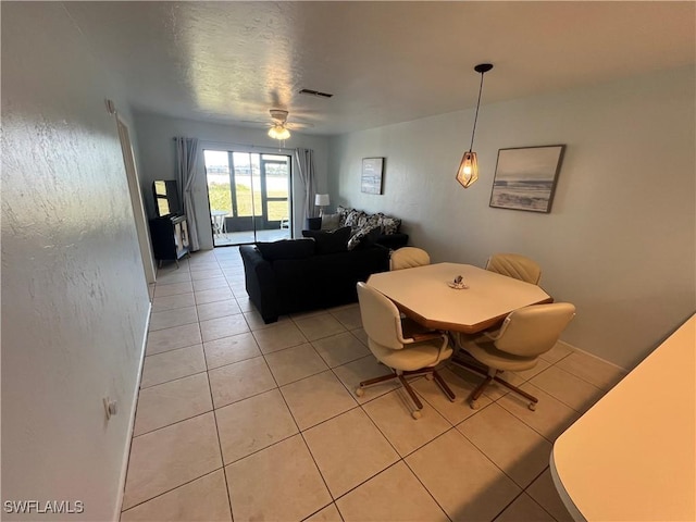 tiled dining space featuring ceiling fan and a textured ceiling