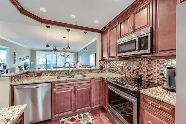 kitchen featuring stainless steel appliances, hanging light fixtures, backsplash, and a sink