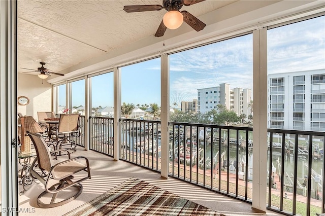 sunroom featuring ceiling fan, a water view, and a city view