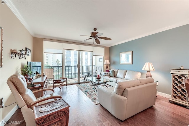 living room featuring a ceiling fan, crown molding, baseboards, and wood finished floors