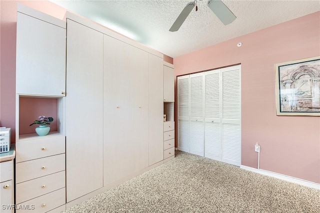 unfurnished bedroom with a textured ceiling, ceiling fan, and carpet