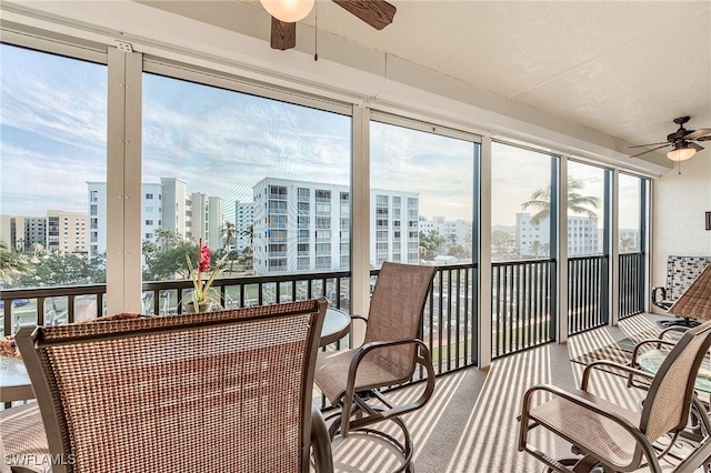 sunroom featuring ceiling fan and a view of city