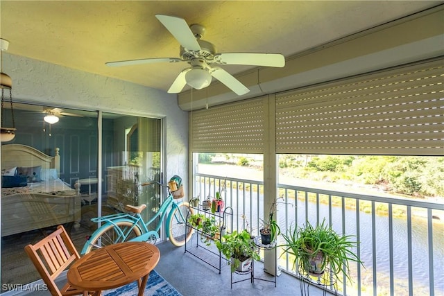 sunroom / solarium featuring ceiling fan and a water view