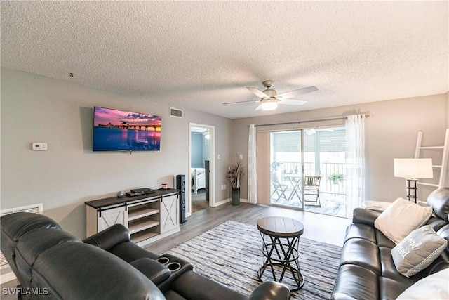 living room with ceiling fan, a textured ceiling, and light wood-type flooring