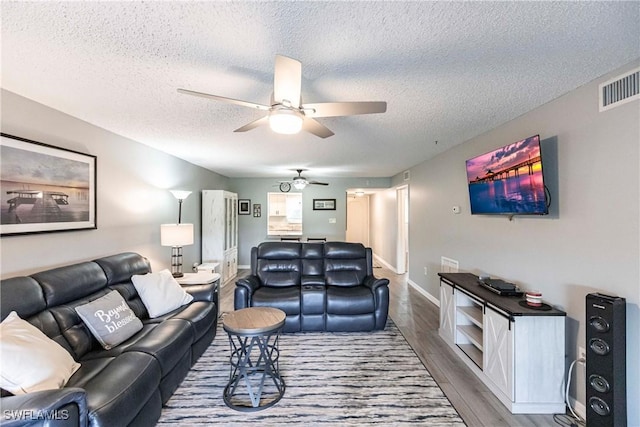 living room with ceiling fan, wood-type flooring, and a textured ceiling