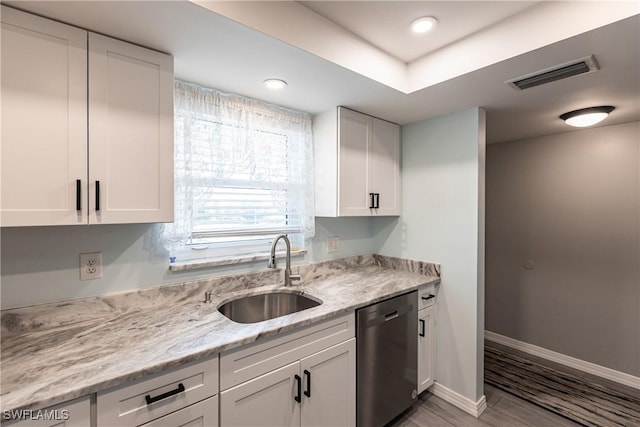 kitchen featuring light stone countertops, stainless steel dishwasher, sink, light hardwood / wood-style floors, and white cabinetry