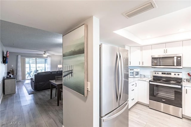 kitchen featuring white cabinets, appliances with stainless steel finishes, and light hardwood / wood-style flooring