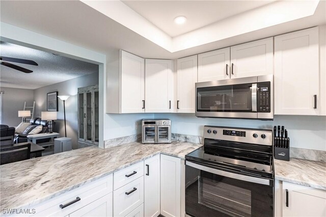 kitchen featuring white cabinetry, ceiling fan, light stone countertops, and appliances with stainless steel finishes