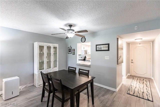 dining room with a textured ceiling, light hardwood / wood-style floors, and ceiling fan