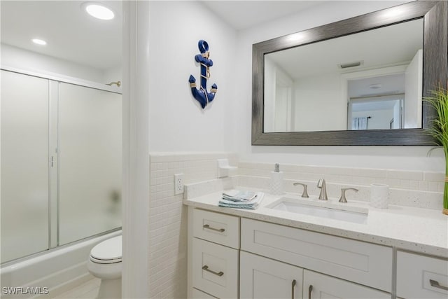 full bathroom featuring vanity, enclosed tub / shower combo, tile walls, and toilet