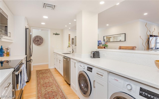 washroom with washer and clothes dryer, light hardwood / wood-style floors, and sink