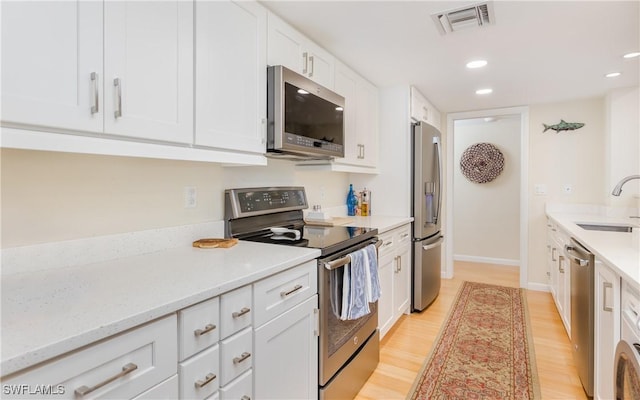 kitchen featuring white cabinetry, sink, stainless steel appliances, light stone counters, and light hardwood / wood-style floors