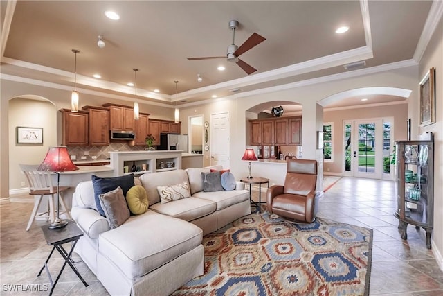 living room with ceiling fan, light tile patterned floors, crown molding, and a tray ceiling