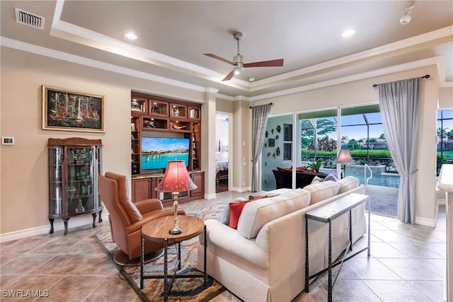 tiled living room featuring a raised ceiling, ceiling fan, and crown molding