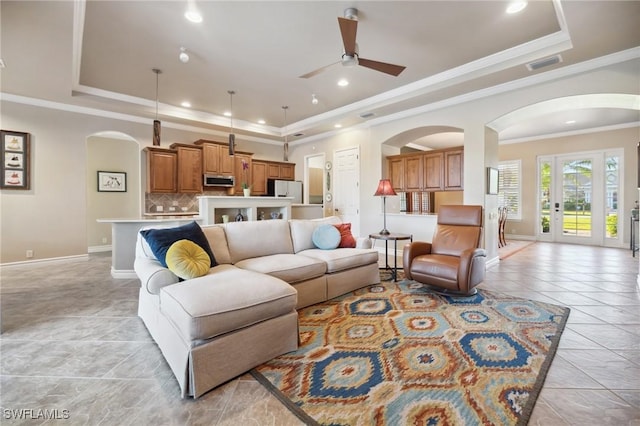 tiled living room featuring ceiling fan, ornamental molding, and a raised ceiling