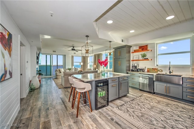 kitchen with dishwasher, sink, wine cooler, light hardwood / wood-style floors, and a kitchen island