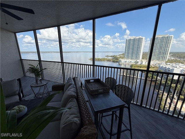 sunroom with a water view and ceiling fan