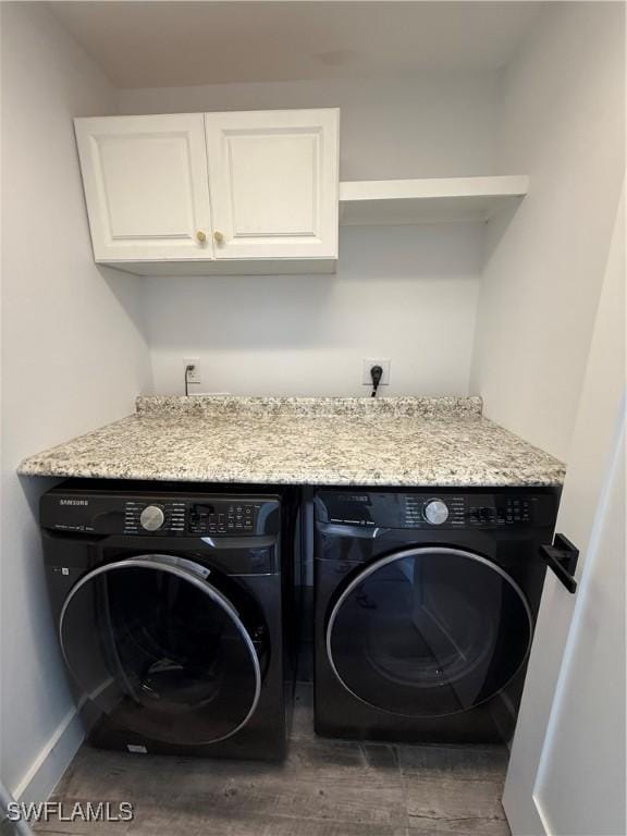 clothes washing area with cabinets and washing machine and dryer