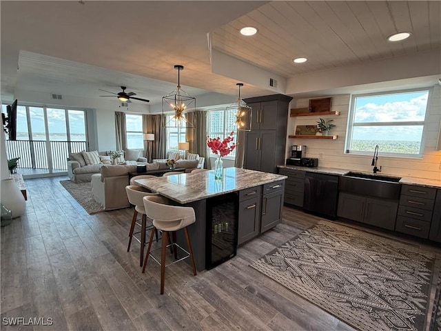 kitchen featuring black dishwasher, sink, beverage cooler, a kitchen bar, and light stone countertops