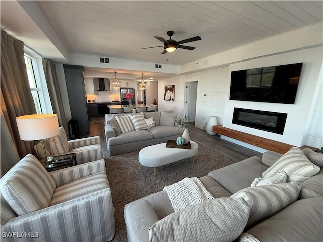 living room featuring dark hardwood / wood-style flooring, ceiling fan with notable chandelier, and wooden ceiling