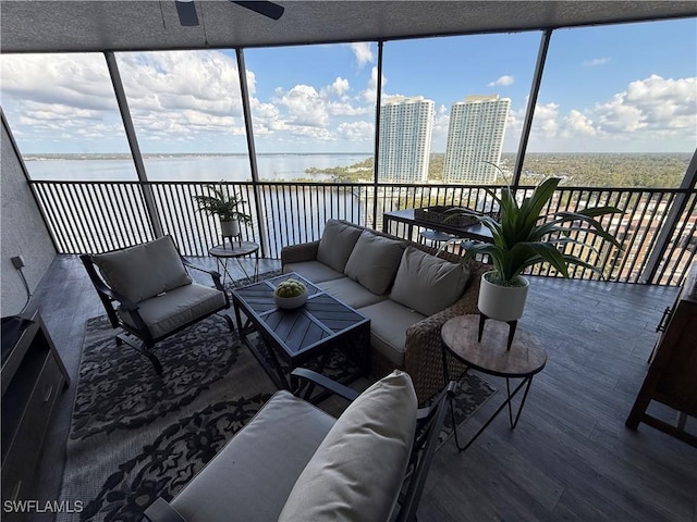 sunroom with a wealth of natural light, ceiling fan, and a water view