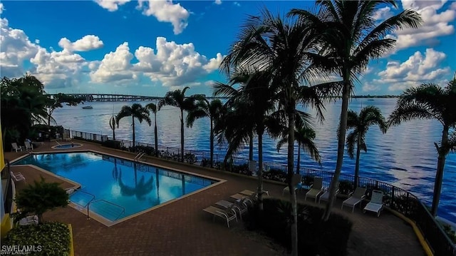 view of pool featuring a hot tub, a patio, and a water view