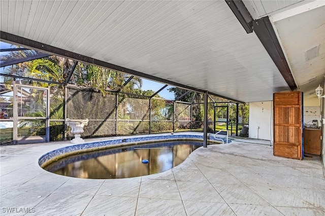 view of swimming pool with glass enclosure and a patio