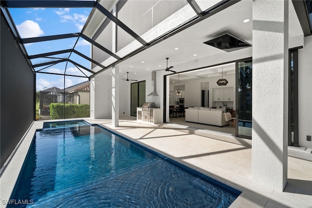 view of pool with an outdoor kitchen, ceiling fan, a patio area, and glass enclosure