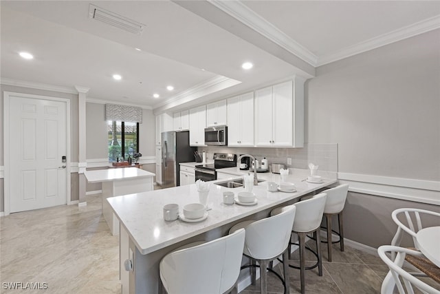 kitchen with stainless steel appliances, kitchen peninsula, white cabinets, and a kitchen bar