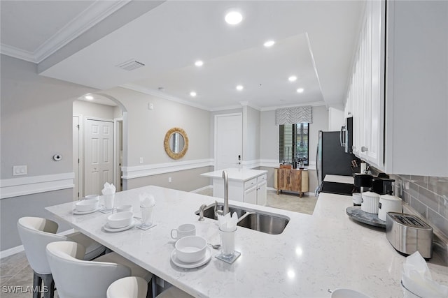 9590 Trevi Ct Unit 5314, Naples, FL 34113 - kitchen with a sink, a kitchen island, arched walkways, white cabinetry, and light stone counters