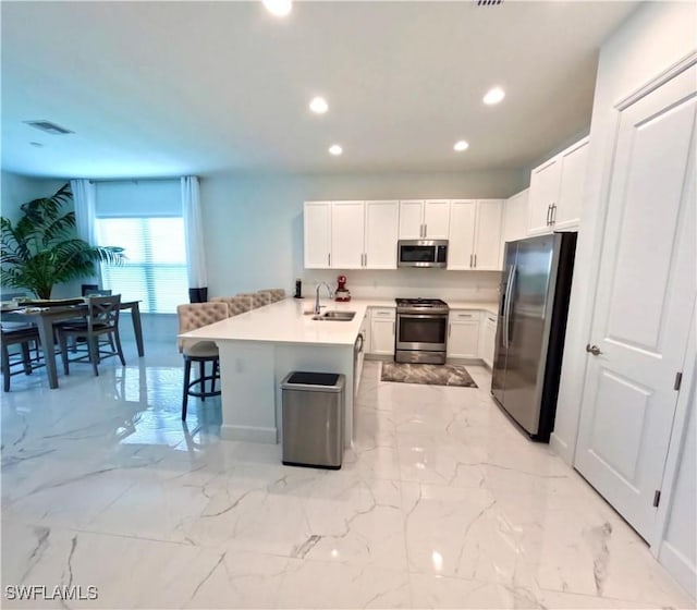 kitchen with a center island with sink, sink, a kitchen bar, white cabinetry, and stainless steel appliances