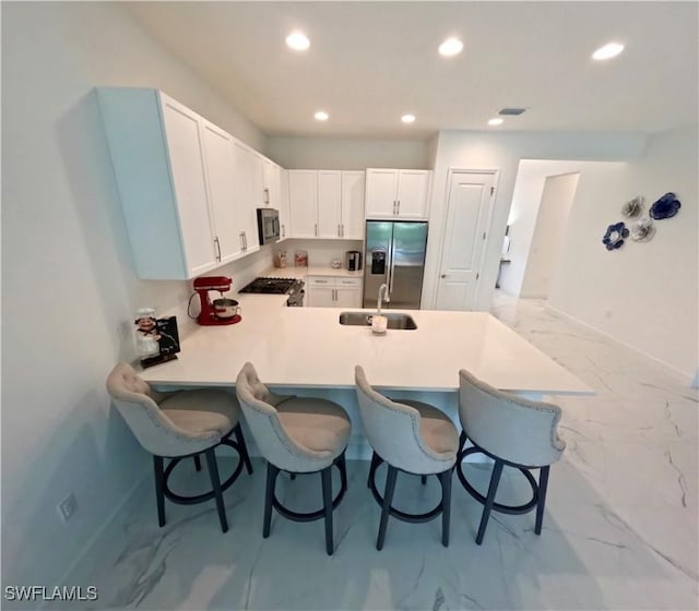 12830 Hawkins Dr, Estero, FL 33928 - kitchen with stainless steel fridge, marble look tiles, a breakfast bar area, recessed lighting, and a peninsula