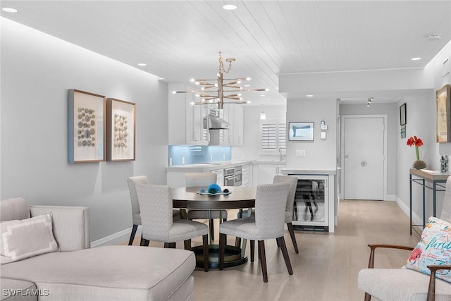 dining area featuring wood ceiling, sink, light hardwood / wood-style flooring, a chandelier, and wine cooler