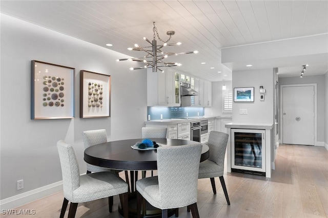 dining room featuring wine cooler, a chandelier, light hardwood / wood-style flooring, and wooden ceiling