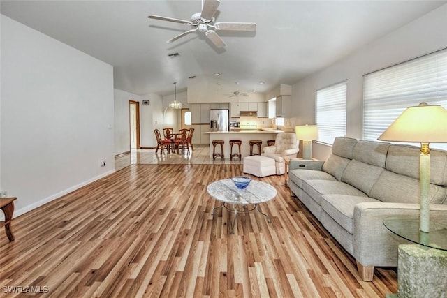 living room featuring light wood-type flooring, ceiling fan, lofted ceiling, and sink