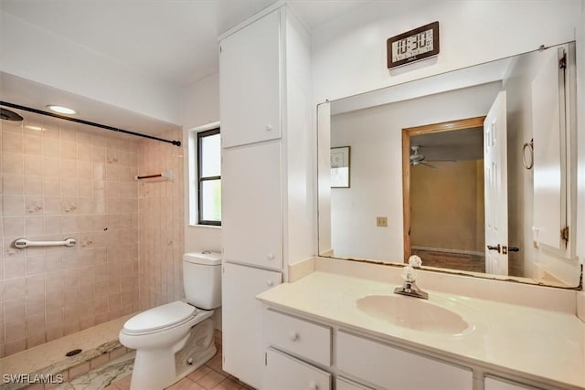 bathroom featuring a tile shower, vanity, toilet, and ceiling fan