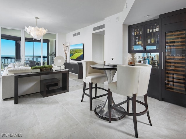 dining area with a water view, an inviting chandelier, and bar