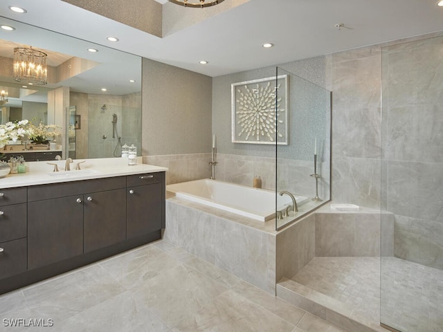 bathroom featuring vanity, independent shower and bath, and an inviting chandelier