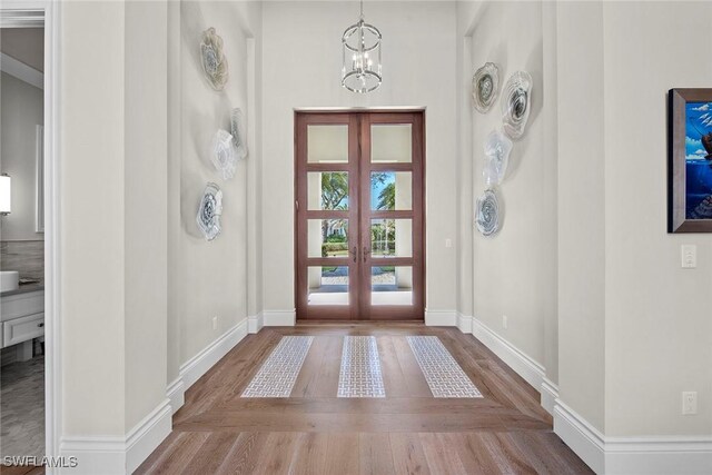 entryway with a notable chandelier, wood-type flooring, and french doors