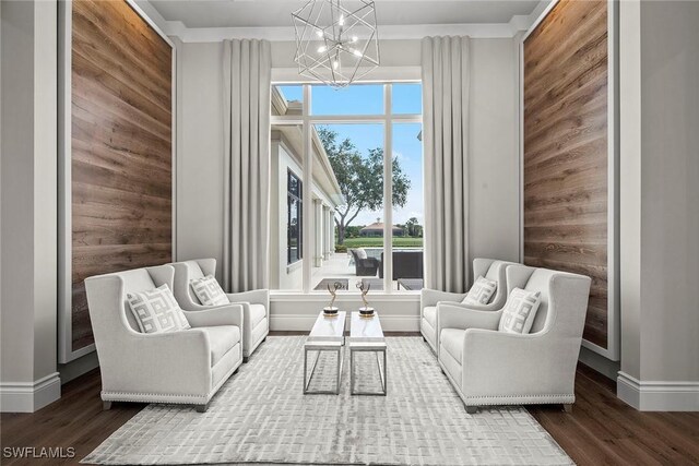 living area featuring hardwood / wood-style floors, an inviting chandelier, and wooden walls