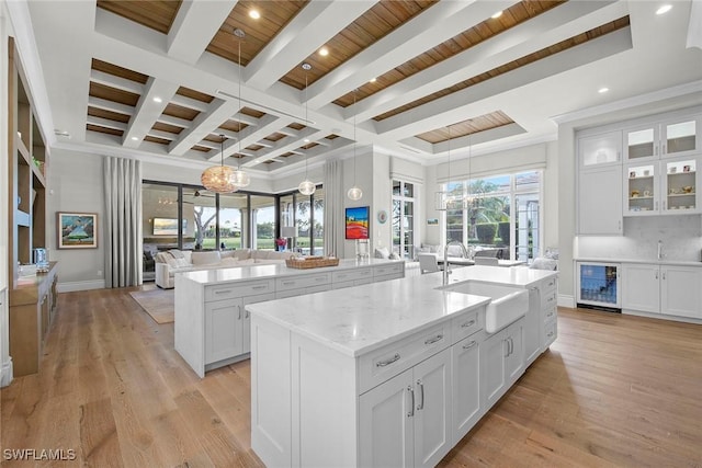 kitchen with white cabinetry, sink, an inviting chandelier, wine cooler, and a spacious island