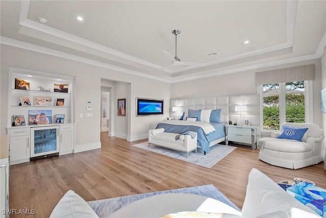 bedroom featuring ceiling fan, light wood-type flooring, beverage cooler, and a tray ceiling