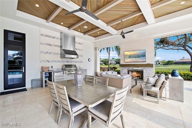 dining area with beamed ceiling, a stone fireplace, ceiling fan, and wood ceiling