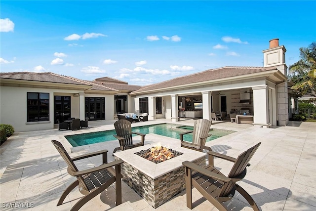 back of house featuring a pool with hot tub, a patio, an outdoor living space with a fire pit, and ceiling fan