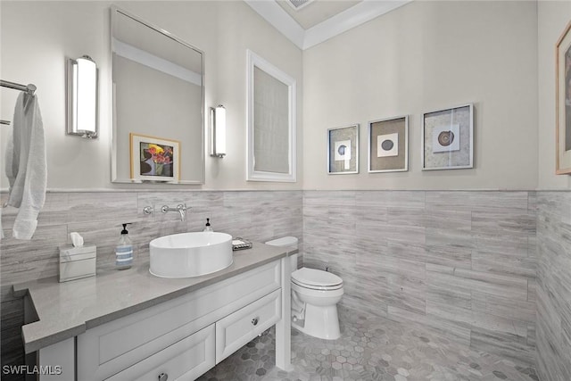 bathroom featuring tile patterned floors, toilet, vanity, tile walls, and ornamental molding