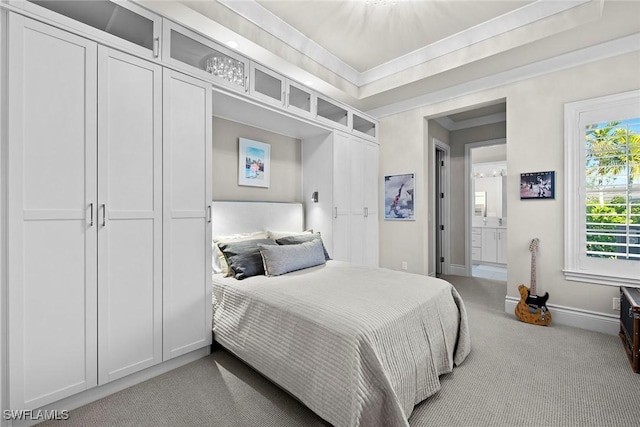 carpeted bedroom featuring ensuite bath and crown molding