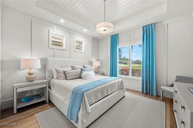 bedroom with a raised ceiling, hardwood / wood-style floors, and wooden ceiling