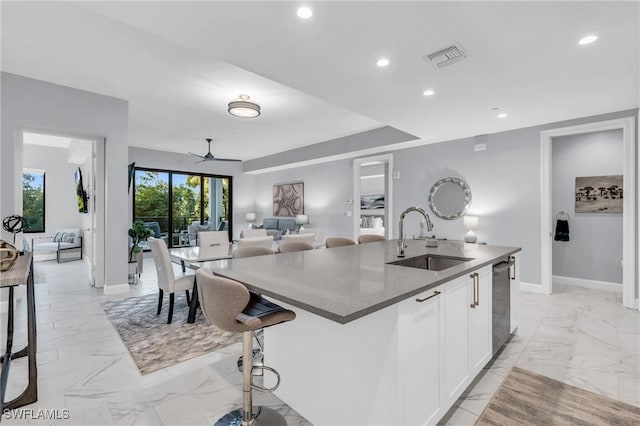 kitchen with white cabinetry, sink, ceiling fan, stainless steel dishwasher, and an island with sink